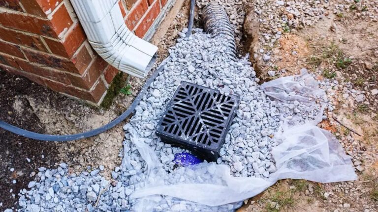 Close-up of a residential stormwater drainage system with a downpipe, gravel bed, and catch basin to direct rainwater away from the foundation – Discover Home Inspections, South Africa.