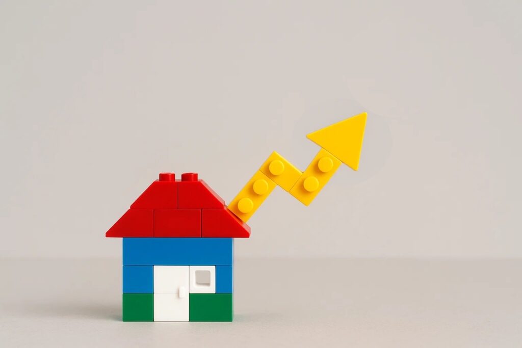 Lego house model with a green upward arrow symbolizing property value growth and investment increase